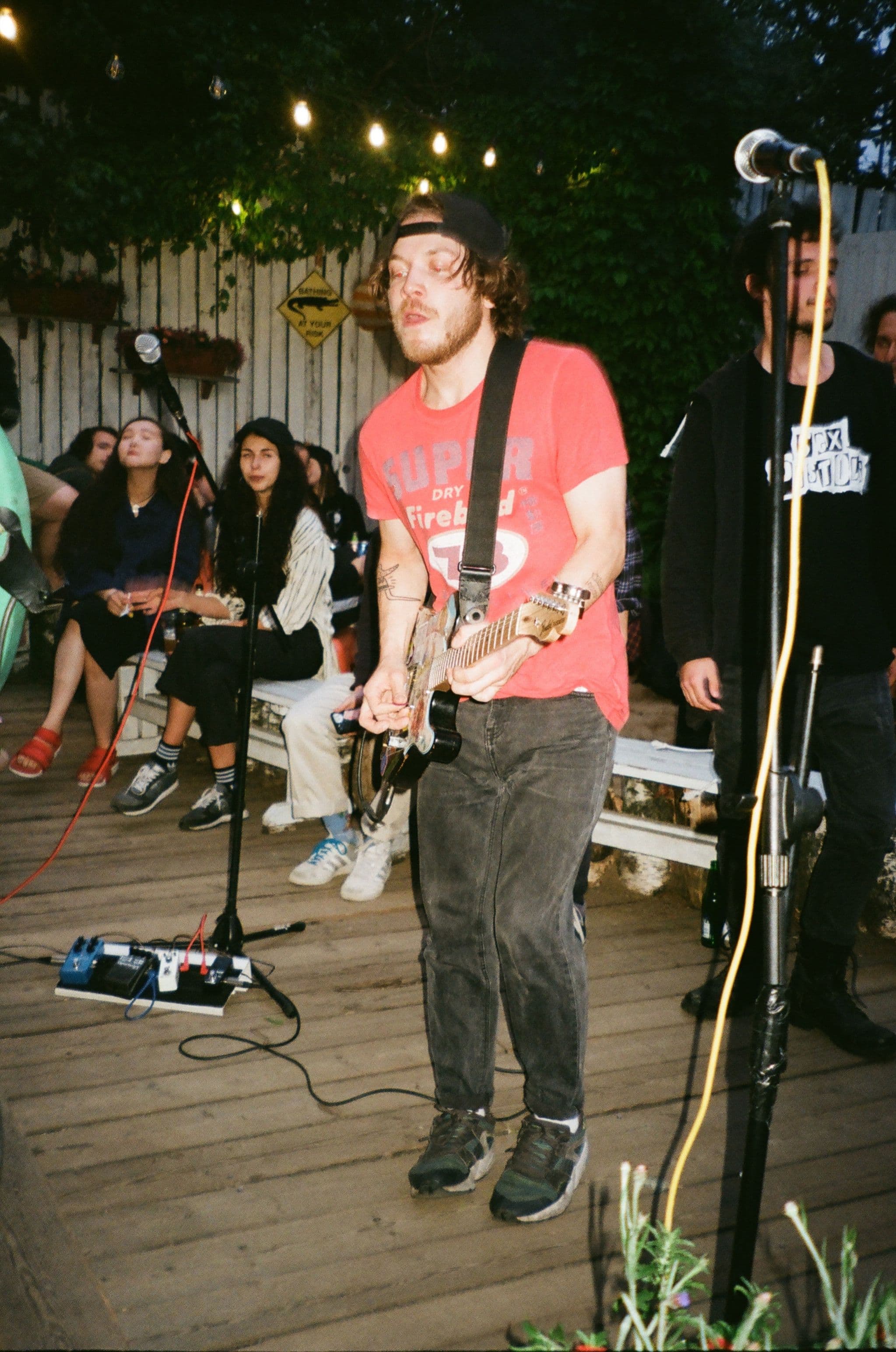 A band playing on a porch under warm string lights at dusk